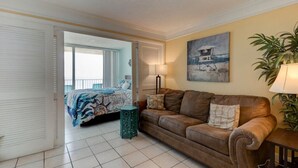 A living room with a brown leather sofa, a green side table, and a painting on the wall. - Sunrise Seven Deluxe Oceanfront Condo (Daytona Beach)