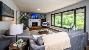 A modern living room with a fireplace, a large window, and a television.