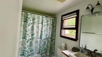 A bathroom with a toilet, sink, and shower curtain.