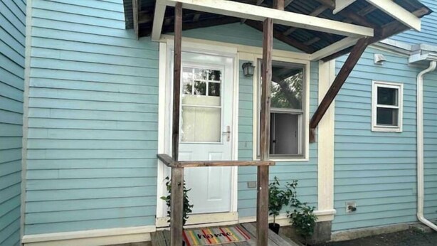 A house with a porch, a white door, and a window. - Traveler’s Den in Medford (Medford)