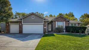 A two-story house with a garage, a well-maintained lawn, and a brick exterior.