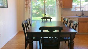 A dining area with a wooden table and chairs, a chandelier, and a view of a backyard through glass doors. - Charming Vacaville Home in Peaceful Neighborhood! (Vacaville)