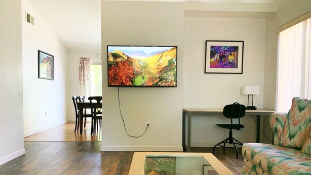A living room with a TV, a sofa, a coffee table, and a dining area. - Charming Vacaville Home in Peaceful Neighborhood! (Vacaville)