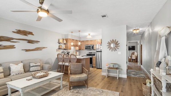 A modern living room with a sofa, chairs, a coffee table, and a ceiling fan.
