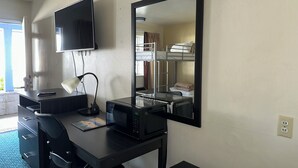Ein Hotelzimmer mit Schreibtisch, Fernseher, Spiegel, Etagenbett und Mikrowelle.