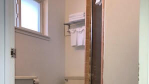 Ein Badezimmer mit Toilette, einem Fenster und einer Duschkabine.
