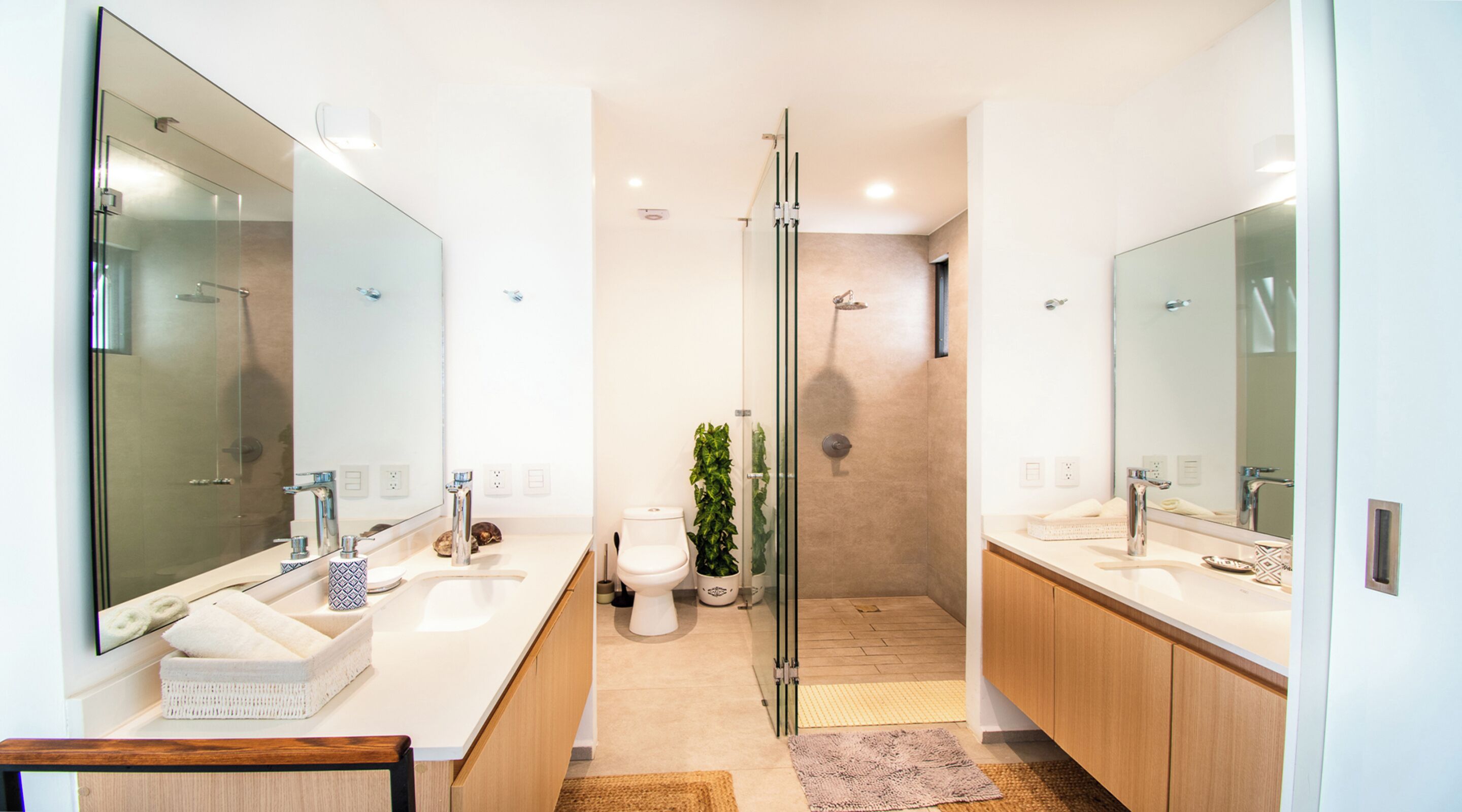 Un baño moderno con cabina de ducha de vidrio, un espejo grande y un lavabo blanco.