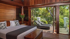 Une chambre avec un grand lit, un banc et un balcon équipé de chaises longues.