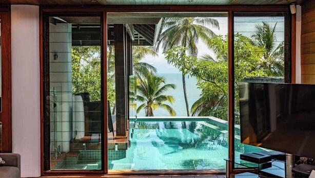 Un intérieur moderne avec une porte vitrée donnant sur un espace piscine, un téléviseur à écran plat et un plafond en bois.