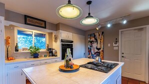 A modern kitchen with a central island, white cabinetry, a built-in oven, and pendant lighting.