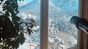 A room with a large window overlooking a snowy mountainous landscape.