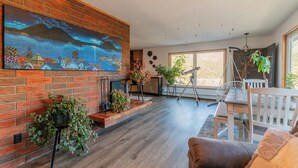 A spacious living room with a brick fireplace, a large painting, and a telescope.