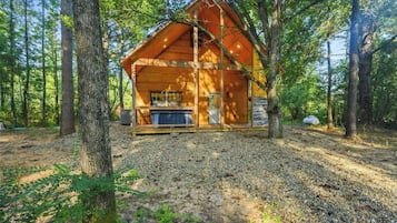 A wooden cabin with a porch, surrounded by trees.