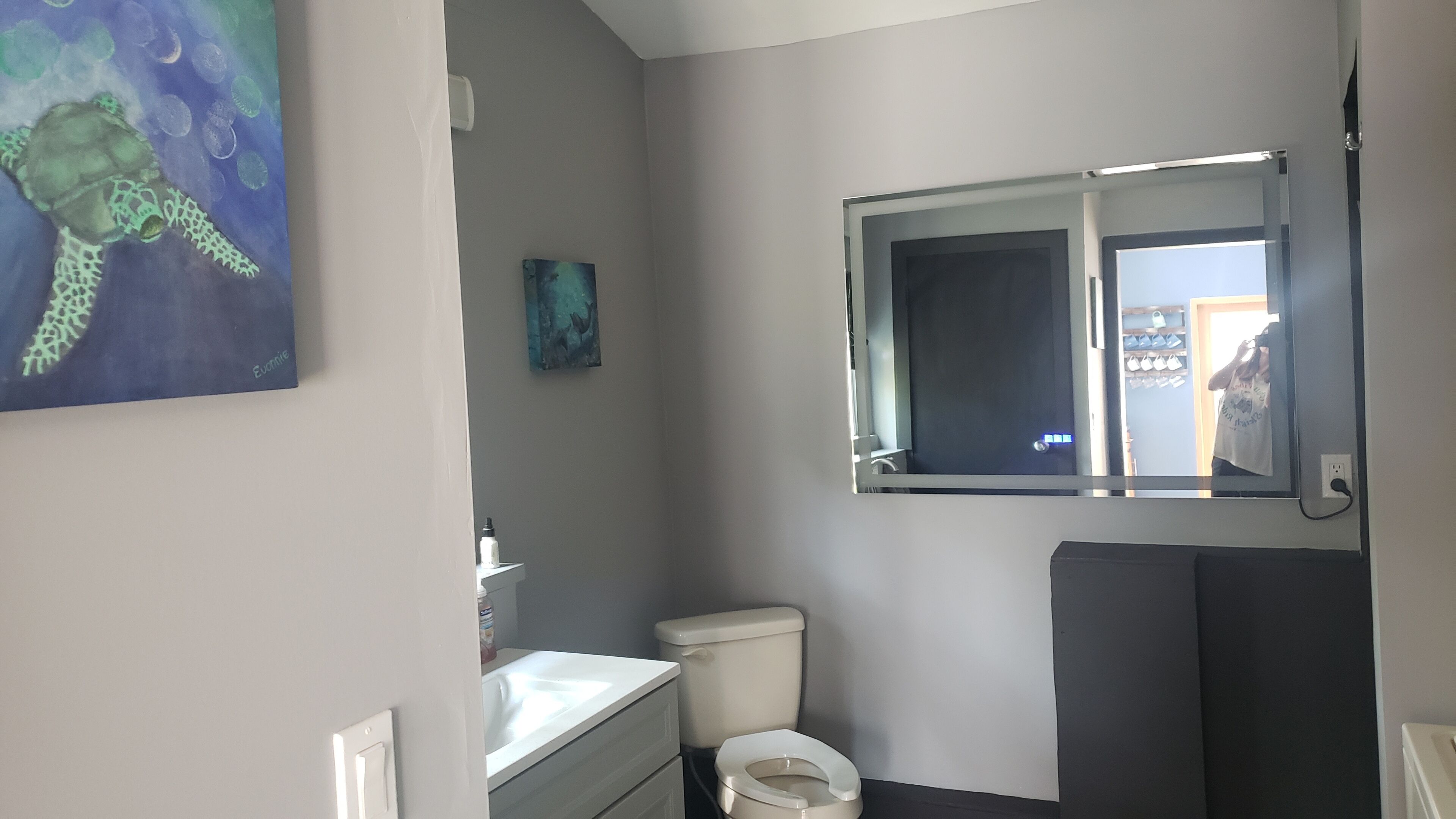 A bathroom with a toilet, sink, and mirror.