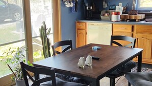 Une cuisine moderne avec des meubles en bois, une table à manger avec des chaises et une grande fenêtre donnant sur l’extérieur.