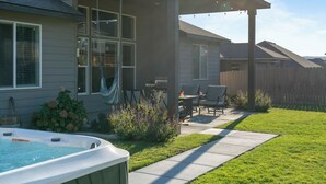 Une maison dotée d’un patio couvert, d’un jacuzzi et d’une clôture en bois.