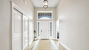 Un couloir doté d’un plancher en bois, de murs blancs et d’une porte blanche avec des panneaux de verre.