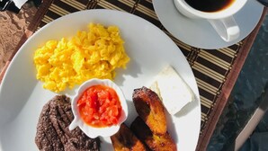 A breakfast plate with scrambled eggs, black pudding, fried plantains, and a small bowl of tomato salsa. - Luna Maya Antigua Hotel (Antigua Guatemala)