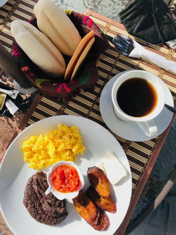 A breakfast plate with scrambled eggs, black pudding, fried plantains, and a small bowl of tomato salsa. - Luna Maya Antigua Hotel (Antigua Guatemala)