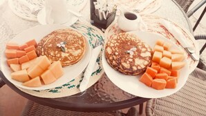 Two plates of pancakes with melon chunks on a round table with a woven placemat. - Luna Maya Antigua Hotel (Antigua Guatemala)