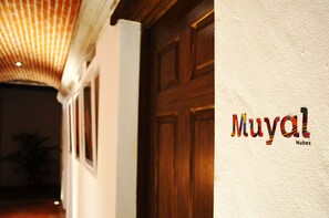 A hallway with a wooden door and a textured wall with the text "Muyang Nubes". - Luna Maya Antigua Hotel (Antigua Guatemala)