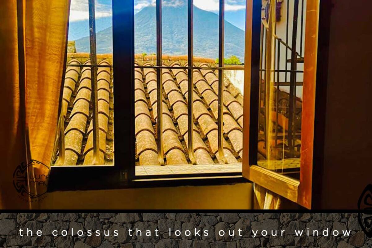 A window with a view of a mountain and tiled roof.