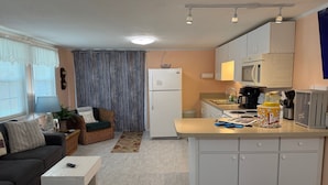 A compact living space with a kitchenette, a sofa, a dining table, and a small kitchen counter. - Off Duty Retreat ~Sleeps 10, Boat Slip, Screen Porch, Lots of Parking, 2 Grills (Steinhatchee)