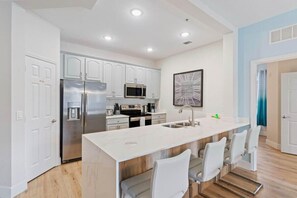 A modern kitchen with white cabinets, stainless steel appliances, and a central island with bar seating. - The Epic 00106 Vista Cay Resort Orlando Florida (Orlando)