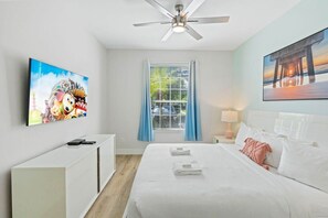 A hotel room with a bed, a ceiling fan, a TV, a window with curtains, and artwork on the walls. - The Epic 00106 Vista Cay Resort Orlando Florida (Orlando)