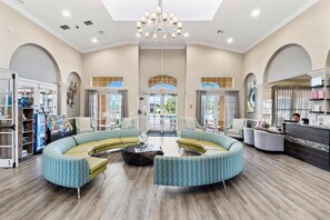 A spacious lobby with a curved seating area, a reception desk, and a large chandelier.