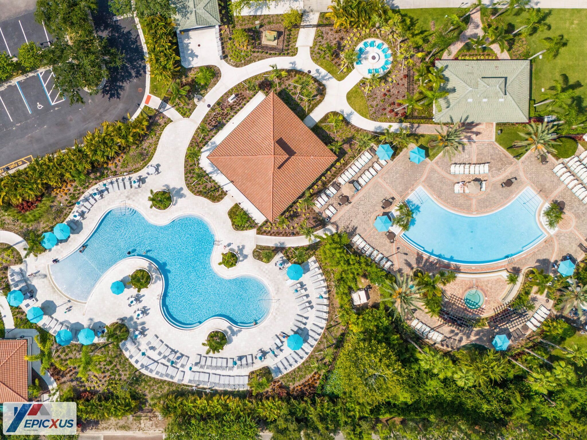 Vista aèria d'un complex turístic amb una piscina central, diverses zones de relaxació i un aparcament.