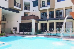 Ett modernt hotell med en swimmingpool, utomhusplats och en vattendekoration.