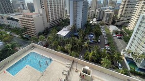 Una piscina en la azotea rodeada de palmeras y rascacielos.