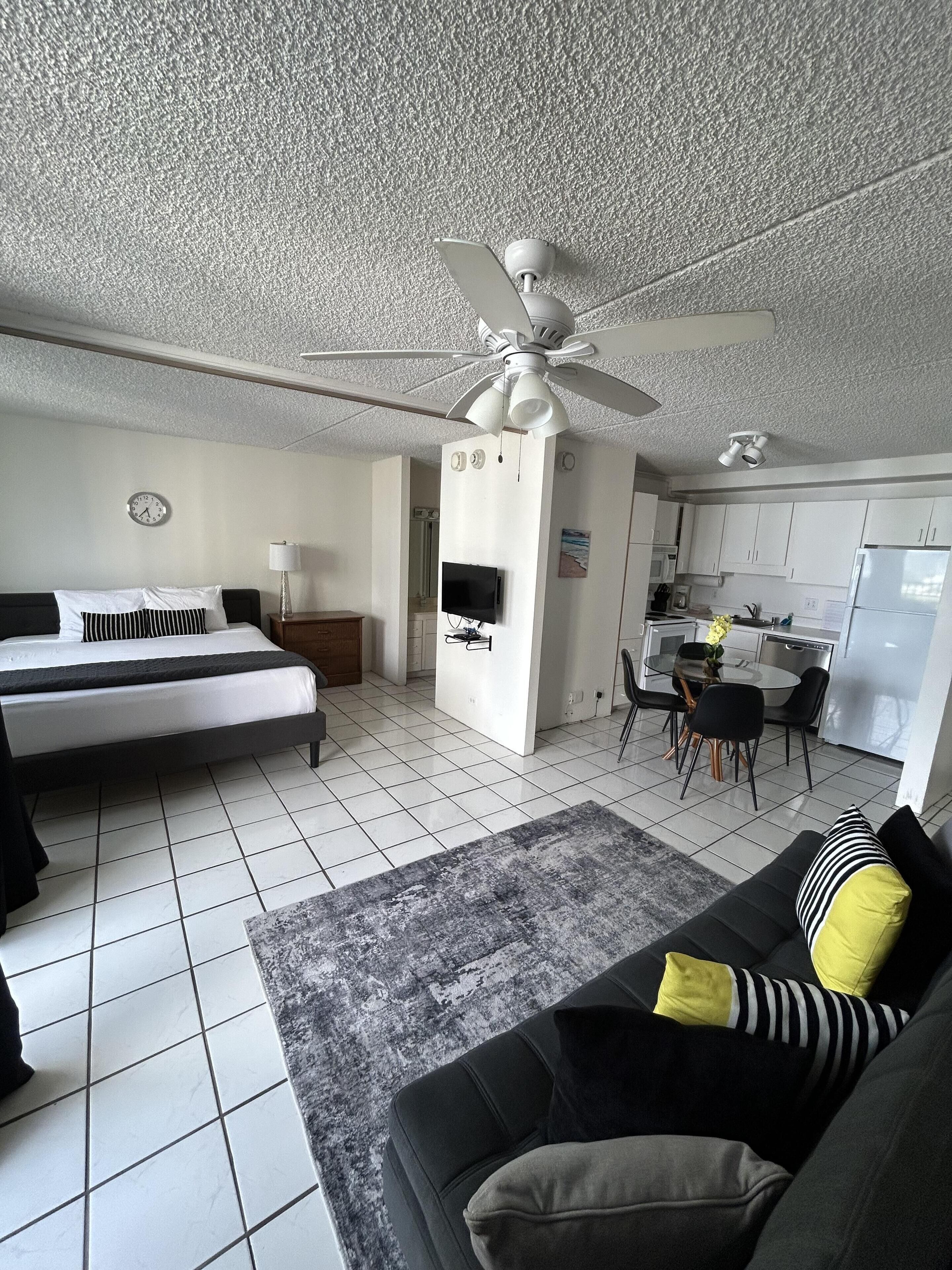 A modern apartment with a bed, a sofa, a dining area, and a kitchen.