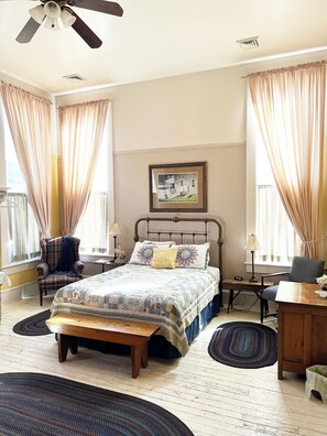A bedroom with a bed, two chairs, a desk, a ceiling fan, and a framed picture on the wall. - Historic rooms near riverfront in downtown, Louisiana, MO (Louisiana)