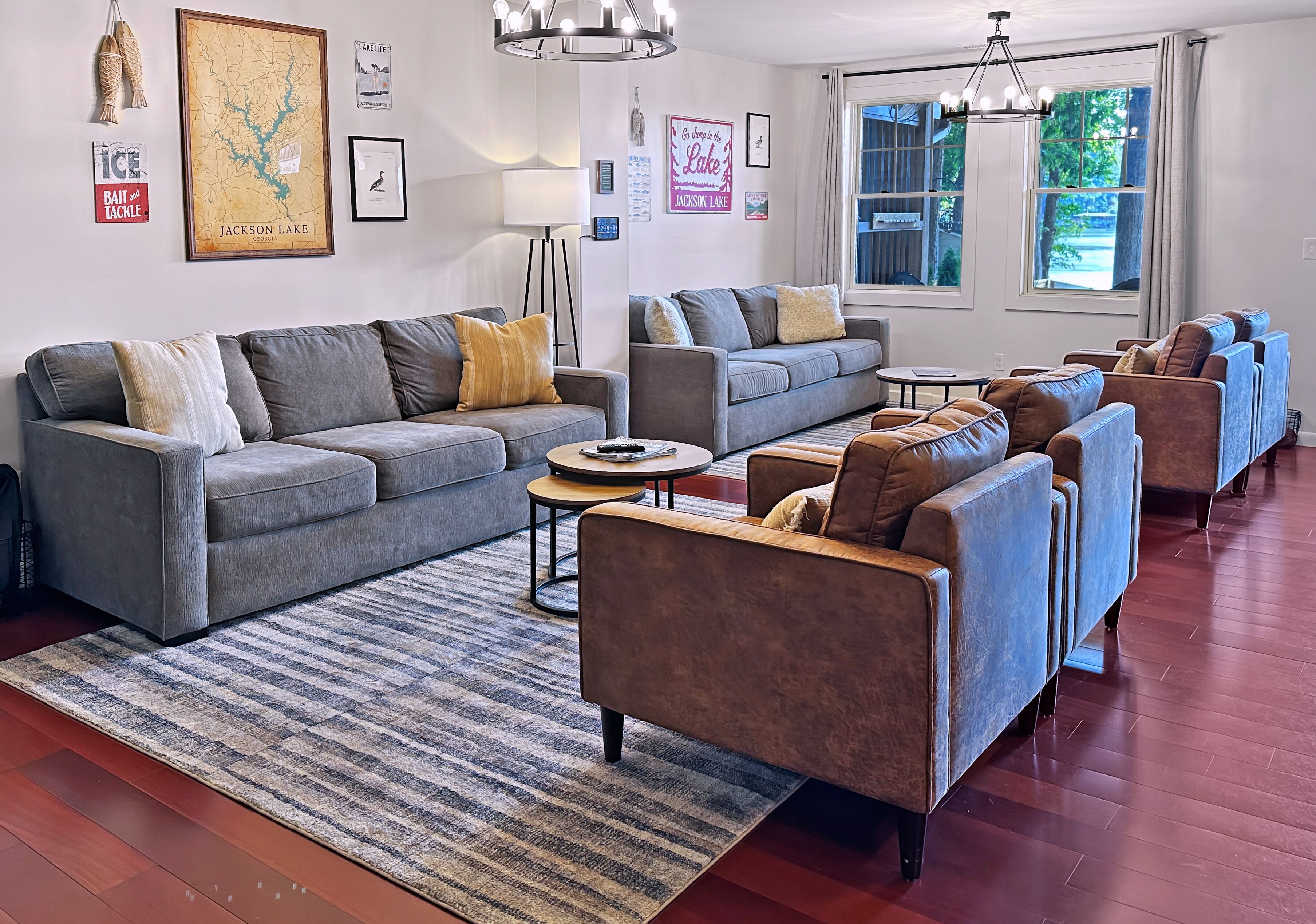 A living room with a grey sofa, a smaller grey couch, and multiple armchairs. There is a coffee table in the center.
