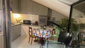 A modern kitchen with a dining area, featuring a glass table, chairs, and a patterned rug. - Fashionable by the canals (Milano)