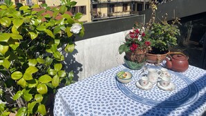 A balcony with a table set for tea, surrounded by potted plants and a view of buildings. - Fashionable by the canals (Milano)