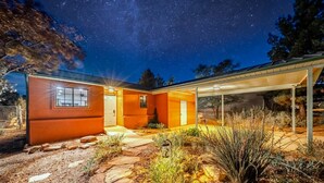 Una casa moderna con patio coperto, vialetto in pietra e vegetazione tipica del deserto.
