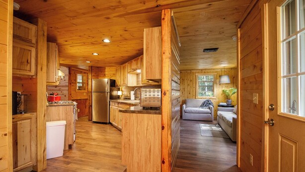 Interior de una cabaña de madera con cocina, comedor y sala de estar.