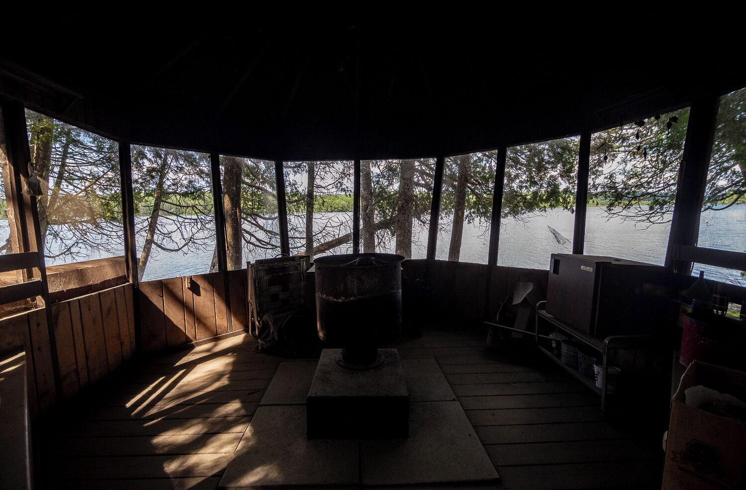 A cabin with a large window overlooking a body of water, a fireplace, and a television.