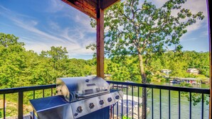 Un balcon doté d’un barbecue, donnant sur un lac et une forêt.