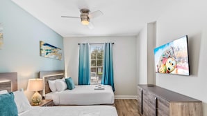 A hotel room with two beds, a ceiling fan, a TV, and a window with curtains.