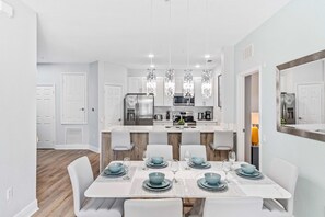 A modern kitchen with white cabinets, stainless steel appliances, and pendant lighting. - The Epic 6 Vista Cay Resort Orlando Florida (Orlando)