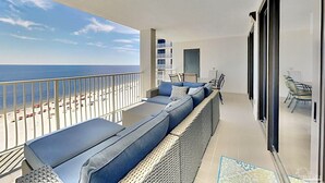 A balcony with a view of the beach and ocean, furnished with a sofa and chairs. - 5 STARS Beachfront Condo, Indoor/Outdoor Pools, Hot Tub & Tennis! BOOK NOW! (Orange Beach)