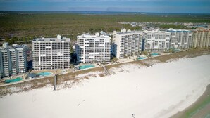 A beachfront hotel complex with multiple high-rise buildings, each featuring balconies and a pool area. - 5 STARS Beachfront Condo, Indoor/Outdoor Pools, Hot Tub & Tennis! BOOK NOW! (Orange Beach)