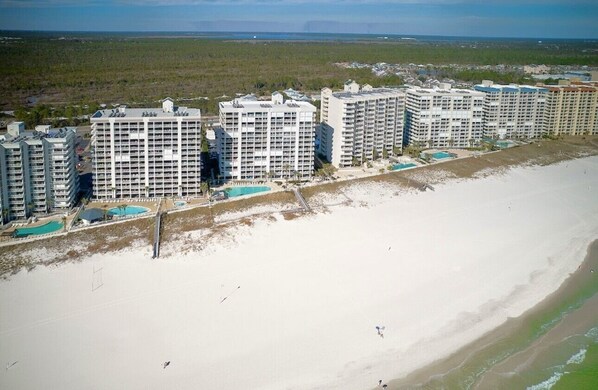 A beachfront hotel complex with multiple high-rise buildings, each featuring balconies and a pool area.
