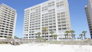 A high-rise hotel with multiple floors, balconies, and a beach view. - 5 STARS Beachfront Condo, Indoor/Outdoor Pools, Hot Tub & Tennis! BOOK NOW! (Orange Beach)