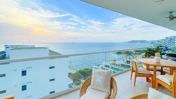 A balcony with a view of the sea and buildings.