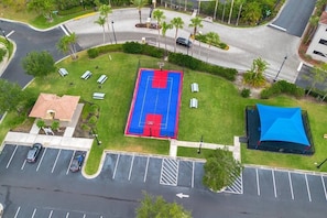 Vista aérea de un estacionamiento con cancha de baloncesto, un área techada y un edificio con techo rojo.
